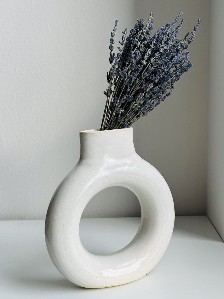 A bunch of dried lavender in a white ring-shaped ceramic vase